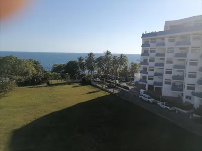 a large building with cars parked next to a grass field at Quiet apartment, good access to Supermarkets, Center etc in Santo Domingo