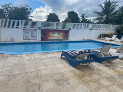 a swimming pool with two lounge chairs next to it at Kasita del sol boca chica in La Caleta