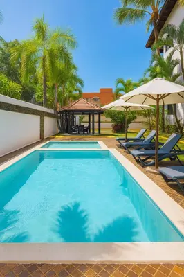 a swimming pool with two lounge chairs and an umbrella at Ocean Front Escape in Las Terrenas