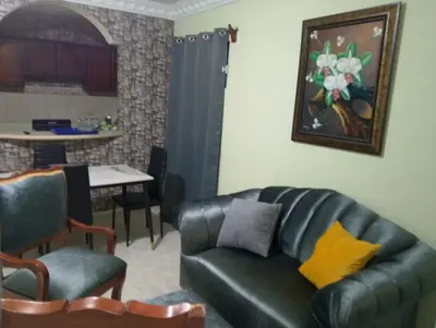 a living room with a black leather couch and a table at confor y seguridad in Santo Domingo