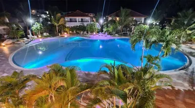 a swimming pool at night with palm trees around it at Residencial Paraiso in Bayahibe