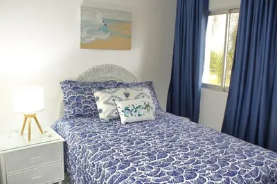 a bedroom with blue curtains and a bed with a pillow at Apartamento Playa Juan dolio in Villas del Mar