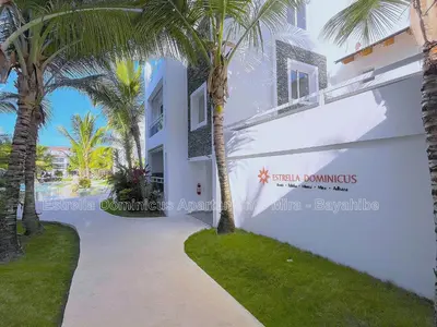 a white building with palm trees in front of it at Estrella Dominicus Apartamento - Bayahibe in Bayahibe