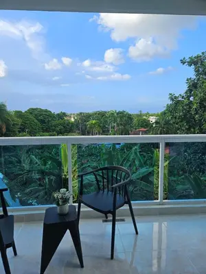 a chair on a balcony with a view of trees at Full Department 2 hab in Las Terrenas