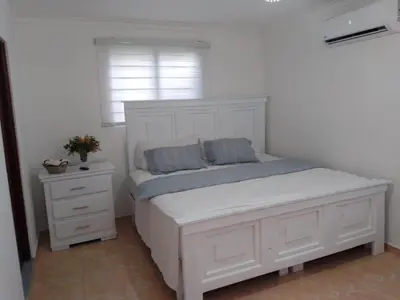 a white bed with two pillows on it in a bedroom at villa cueva del padre pio in Santiago de los Caballeros