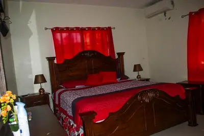a bedroom with a wooden bed with red curtains at Casa de alquiler FIGARO in Villa Clara