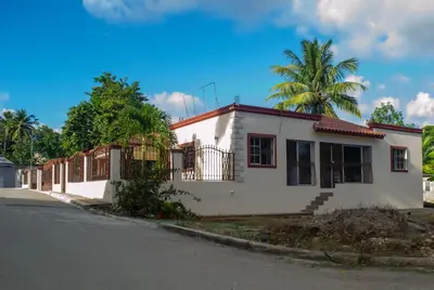 a white house with a palm tree in the background at Casa de alquiler FIGARO in Villa Clara