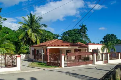 a small house with a fence and palm trees at Casa de alquiler FIGARO in Villa Clara