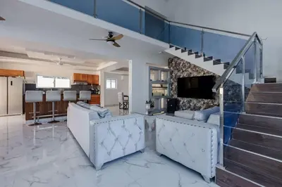 a living room with blue ceilings and a staircase at Luxurious Home with Pool in San Felipe de Puerto Plata