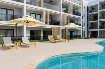 a swimming pool with chairs and umbrellas next to a building at Bran new condo with pool access in Punta Cana