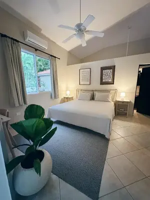 a bedroom with a white bed and a ceiling fan at Casa Caipirinha Encuentro in Cabarete