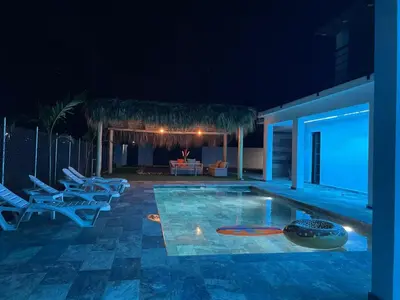 a swimming pool at night with chairs and a table at Apartamento Entre Playas 1 - 3 pax, 4 min de la playa in Las Galeras