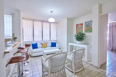 a living room with a white couch and chairs at A Beautiful Studio Apartments Furnished in Gascue in Santo Domingo