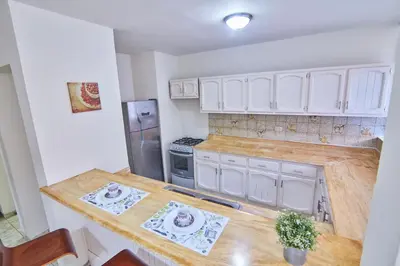 a kitchen with white cabinets and a wooden counter top at A Beautiful Studio Apartments Furnished in Gascue in Santo Domingo