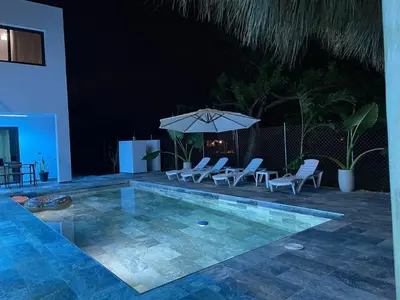 a swimming pool with chairs and an umbrella at Apartamento Entre Playas - 5 pax, 4 min de la playa in Las Galeras