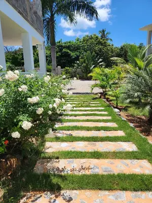 a stone path leading to a house with flowers at Bella Villa room with kitchenette, pool and close to the beach in Las Galeras in Las Galeras