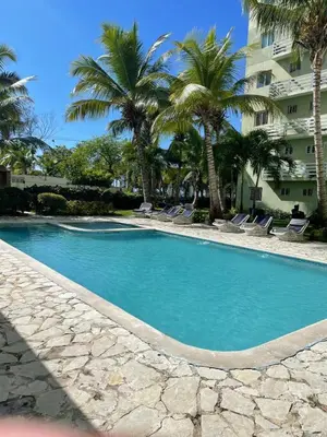a swimming pool with palm trees and a building at Gran Apartamento frente al mar in La Francia