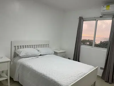 a white bedroom with a bed and a window at Vista al Caribe in Los Mameyes