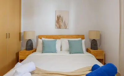 a bedroom with a bed with blue pillows and two lamps at Amazing pool views apartment in Playa Bavaro in Punta Cana
