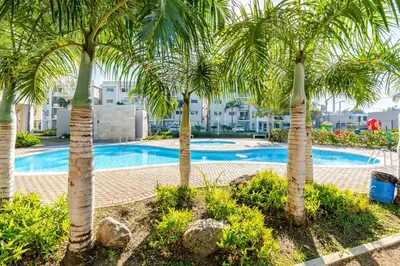 a group of palm trees in front of a swimming pool at Chic Urban Retreat with Pool, Gym, & Free Parking in Santiago de los Caballeros