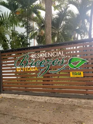 a sign on a fence with palm trees in the background at Chic Urban Retreat with Pool, Gym, & Free Parking in Santiago de los Caballeros