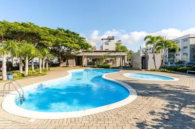 a swimming pool in a resort with trees and buildings at Chic Urban Retreat with Pool, Gym, & Free Parking in Santiago de los Caballeros