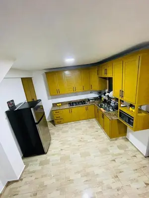 a kitchen with yellow cabinets and a black refrigerator at Villa Estela Jarabacoa in Jarabacoa