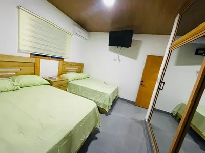 a room with two beds and a television in it at Villa Estela Jarabacoa in Jarabacoa