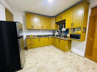 a kitchen with yellow cabinets and a black refrigerator at Villa Estela Jarabacoa in Jarabacoa