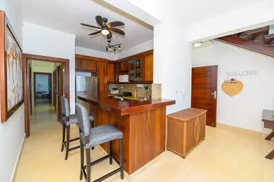 a kitchen with a bar with chairs and a ceiling fan at Bluegreen Oceanfront Condo at Laguna Beach in Sosúa