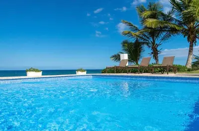 a swimming pool with palm trees and the ocean at Bluegreen Oceanfront Condo at Laguna Beach in Sosúa