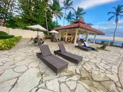a patio with chairs and a gazebo next to the ocean at Spacious apartment beach access in Juan Dolio