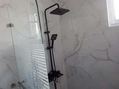 a shower in a bathroom with a marble wall at APE Dream Villa in Itabo