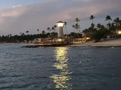 a lighthouse on a beach with palm trees and the water at Casa CASTILLO in La Laguna