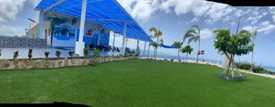 a building with a green lawn next to the ocean at Sundown Relaxed in Punta Rucia