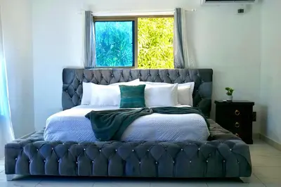 a bed with a blue tufted headboard in a bedroom at Villa Pravda Paradise Guerra in La Caoba