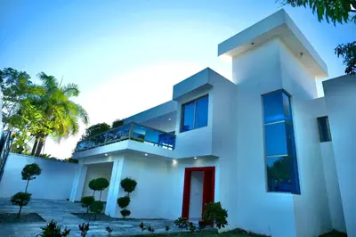 a white house with a red door at Villa Pravda Paradise Guerra in La Caoba