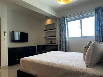 a bedroom with a bed and a desk and a television at Armonia 17 suites by Yellowkey in Santo Domingo