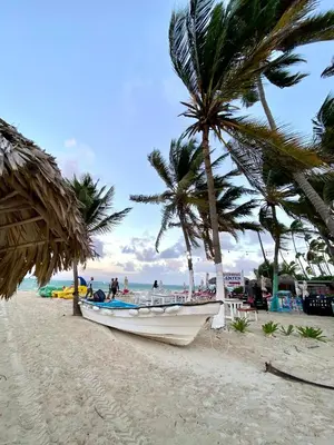 a boat sitting on a beach with palm trees at Cocotal 2beds apartament Golf Course Melia Beach PC RD in Punta Cana