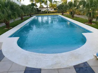 a swimming pool in a yard with palm trees at Gorgeous apartment steps to Playa Punta Popy in Las Terrenas