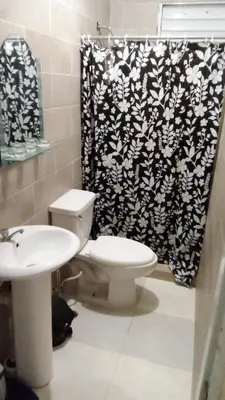 a bathroom with a toilet and a shower curtain at Chez Guela in Mandinga