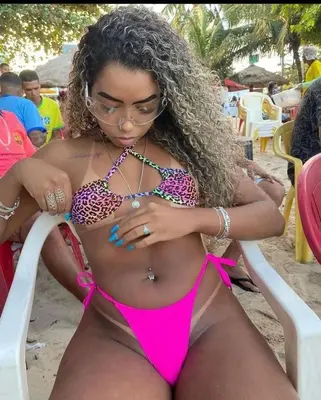 a woman in a pink bikini sitting on a beach at Loteria florida in Higuey