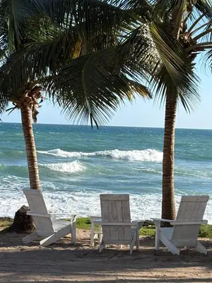 two chairs and palm trees on the beach at Albatros Cozy Apt in Juan Dolio