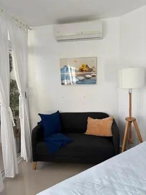 a living room with a black couch in a bedroom at Albatros Cozy Apt in Juan Dolio