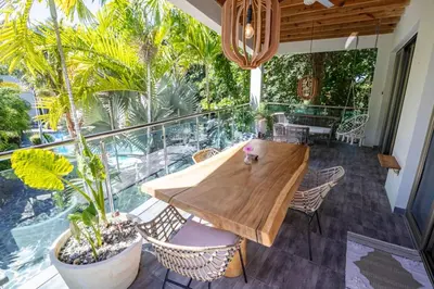 a wooden table and chairs on a balcony with plants at ProCab Kaya Apartments Cabarete in Cabarete