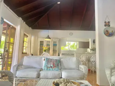 a living room with a white couch and a kitchen at Beach Cabin Juan Dolio in Villas del Mar