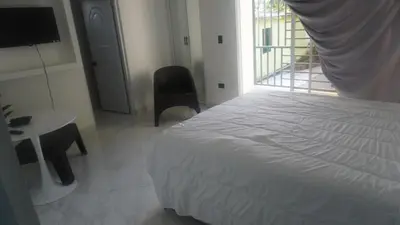 a bedroom with a bed and a desk and a window at Aparta Hotel Ana Julia in Sosúa