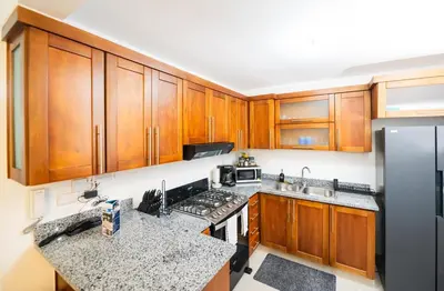 a kitchen with wooden cabinets and a black refrigerator at Blue Lux in Santiago de los Caballeros