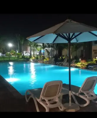 two chairs and an umbrella next to a swimming pool at Flamingo Villa in Boca Paraiso in Boca Chica