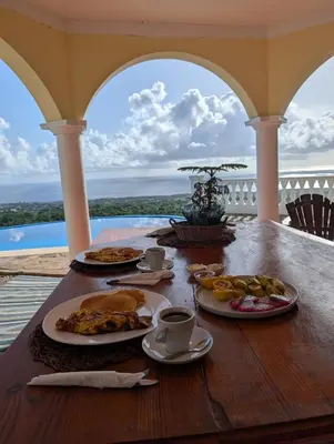 a table with plates of food and coffee on a porch at Desconéctate de la civilización in Nagua